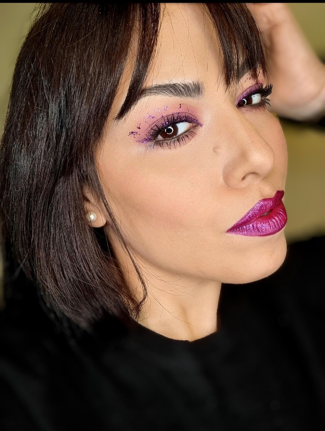 Close-up portrait of a bold makeup look with scattered purple glitter eye makeup and a matching metallic fuchsia lip created by Makeover by Rafaella.